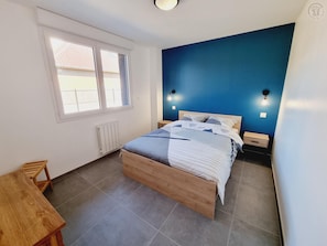 Ein Schlafzimmer mit Bett, Nachttischen, einem Fenster und Blick ins Freie.
