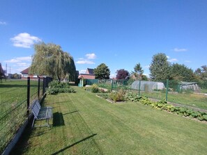 Ein gepflegter Garten mit Rasen, verschiedenen Pflanzen und einem Zaun.