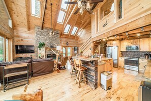 Ein großzügiges Blockhaus mit Wohnbereich, Küche und Kamin aus Stein.