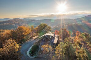 Une cabane dotée d’un porche, entourée de collines boisées.