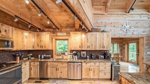 Cocina de cabaña de madera con armarios de madera, electrodomésticos de acero inoxidable y encimera de granito.