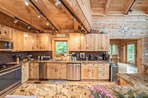 Eine Blockhausküche mit Holzausstattung, Edelstahlgeräten und einer Arbeitsplatte aus Granit.