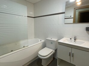 Une salle de bain équipée d’une baignoire, de toilettes, d’un lavabo et d’un miroir.