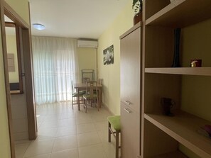Une pièce comprenant une table à manger, des chaises, un buffet et une fenêtre avec des rideaux.