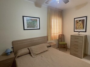 Une chambre à coucher comprenant un lit, une chaise, une commode et deux tableaux encadrés accrochés au mur.