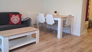 Un salon moderne comprenant un canapé, une table basse, une table à manger avec des chaises et une petite plante.