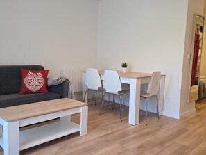 A modern living room with a sofa, a coffee table, a dining table with chairs, and a small plant. - Modern studio near slopes - 4 guests (Aisa-Candanchú)
