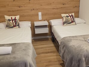 A hotel room with two beds, wooden headboard, bedside tables, and a nightstand. - Modern studio near slopes - 4 guests (Aisa-Candanchú)