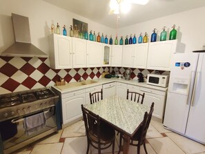 A kitchen with white cabinets, a gas stove, a microwave, and a refrigerator. - Spacious house by the Canal - 14 guests (Argeliers)