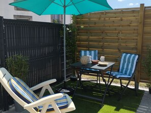 A patio with a table, two chairs, a woven basket, and a blue umbrella. - Cozy independent house - 2 guests (Saint-Étienne-lès-Remiremont)