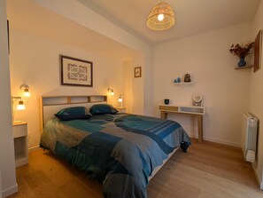A bedroom with a bed, bedside lamps, a desk, a radiator, and a hanging light fixture. - Cozy independent house - 2 guests (Saint-Étienne-lès-Remiremont)