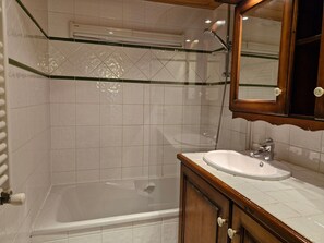 A bathroom with a glass shower enclosure, a white sink with a wooden vanity, and a mirror above the sink. - Charming apartment mountain view - 6 guests (Les Arcs 1800)