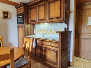 Eine Küche mit Holzausstattung, Fliesenrückwand, Spüle und Herd.