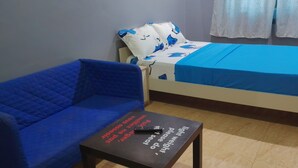 A room with a blue sofa, a bed with a blue bedspread, and a small table with a remote control. - Room-budget Studio Room In Lome Togo (Lomé)