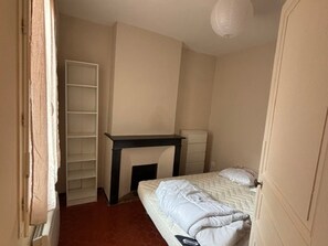 A bedroom with a bed, a bedside table, a wardrobe, and a small desk. - Cozy apartment in city center - 2 guests (Narbonne)