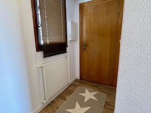 Ein Flur mit einer Holztür, einem Heizkörper und einem Teppich mit Sternenmuster.