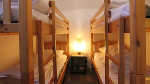 Een kamer met stapelbedden, een nachtkastje met een lamp en een klein nachtkastje.