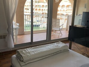 Ein Hotelzimmer mit großem Fenster, einem Bett, einem Sessel und einem Fernseher.