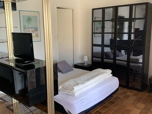 Ein Hotelzimmer mit Bett, Schreibtisch mit Fernseher, Nachttisch und Kleiderschrank.