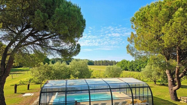 A glass-enclosed pool area with lounge chairs, surrounded by trees and a clear sky. - House with pool, pets allowed - 12 guests (Monsaguel)