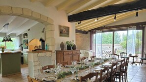 A dining area with stone walls, wooden beams, and a long table set for a meal. - House with pool, pets allowed - 12 guests (Monsaguel)