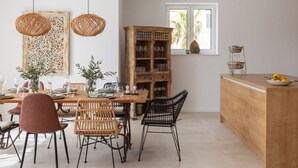 A dining area with a wooden table, wicker chairs, and a wooden cabinet with wine glasses. - Villa Vespera (Makarska)