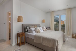 Ein Schlafzimmer mit Bett, Nachttischen und Blick ins Freie.
