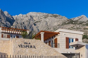 Villa Vespera mit Stein-Fassade, Holz-Pergola und Bergkulisse.