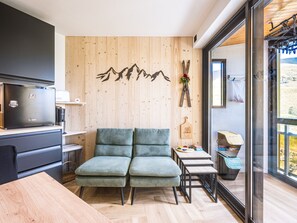 Eine moderne Küche mit eingebautem Herd, Holzvertäfelung und einer Sitzecke inklusive Sofa und kleinen Tischen.