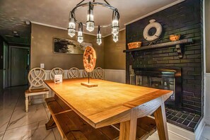 A dining area with a wooden table, chairs, a chandelier, a fireplace, and a painting on the wall. - Moss drive retreat - Close to the woods (Douglasville)
