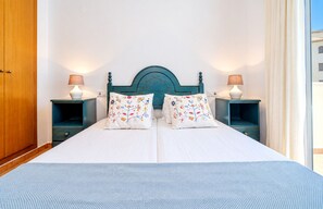 Un lit double agrémenté d’oreillers à motifs floraux, d’une tête de lit turquoise et de lampes de chevet.
