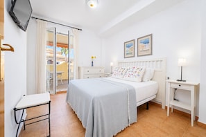 Ein Schlafzimmer mit Bett, Nachttischen, einem Fernseher, einem Sessel und einem Balkon mit Aussicht.