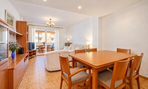 Un coin repas avec une table et des chaises en bois, un canapé et un téléviseur en arrière-plan.