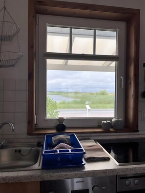 Eine Küche mit Fenster, Spüle, Herd und einer blauen Aufbewahrungsbox.