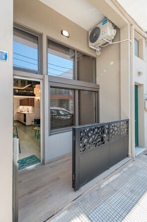 A modern apartment with a balcony, a kitchen visible through the window, and an air conditioning unit mounted on the wall. - Echo City Loft by Rentals Pro - Nea Moudania Halkidiki (Nea Moudania)