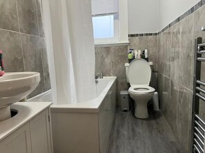 A bathroom with a toilet, sink, and bathtub. - 3 Bedroom Flat - Sleeps 6 - Free Parking (Kirkcaldy)