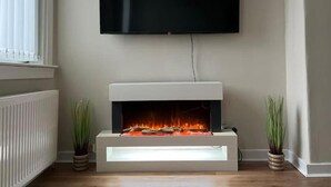 Una sala de estar moderna con un televisor de pantalla plana sobre una chimenea, flanqueada por dos plantas en macetas.