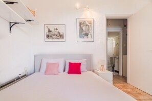 A bedroom with a bed, bedside tables, and a door leading to a bathroom. - Vaya`s Maisonette by RentalsPro - Polychrono Halkidiki (Pallini)