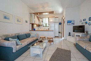 A living room with a sofa, coffee table, and a TV. - Vaya`s Maisonette by RentalsPro - Polychrono Halkidiki (Pallini)