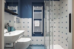 Et badeværelse med hvid vask, toilet og bruseområde.