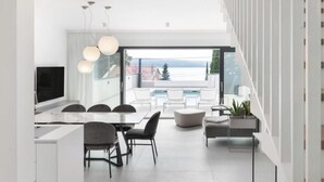 A modern interior with a dining area, kitchen, and large windows offering a view of the outdoors. - Villa XeMa (Dramalj)