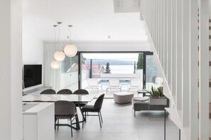 Ein modernes Interieur mit Essbereich, Küche und großen Fenstern mit Blick ins Freie.