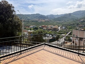 Ein Balkon mit Blick auf eine Stadt, eine Straße und einen Hügel.