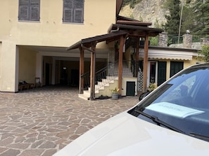 Ein Gebäude mit einem gepflasterten Innenhof, einer Treppe und einem parkenden Auto davor.
