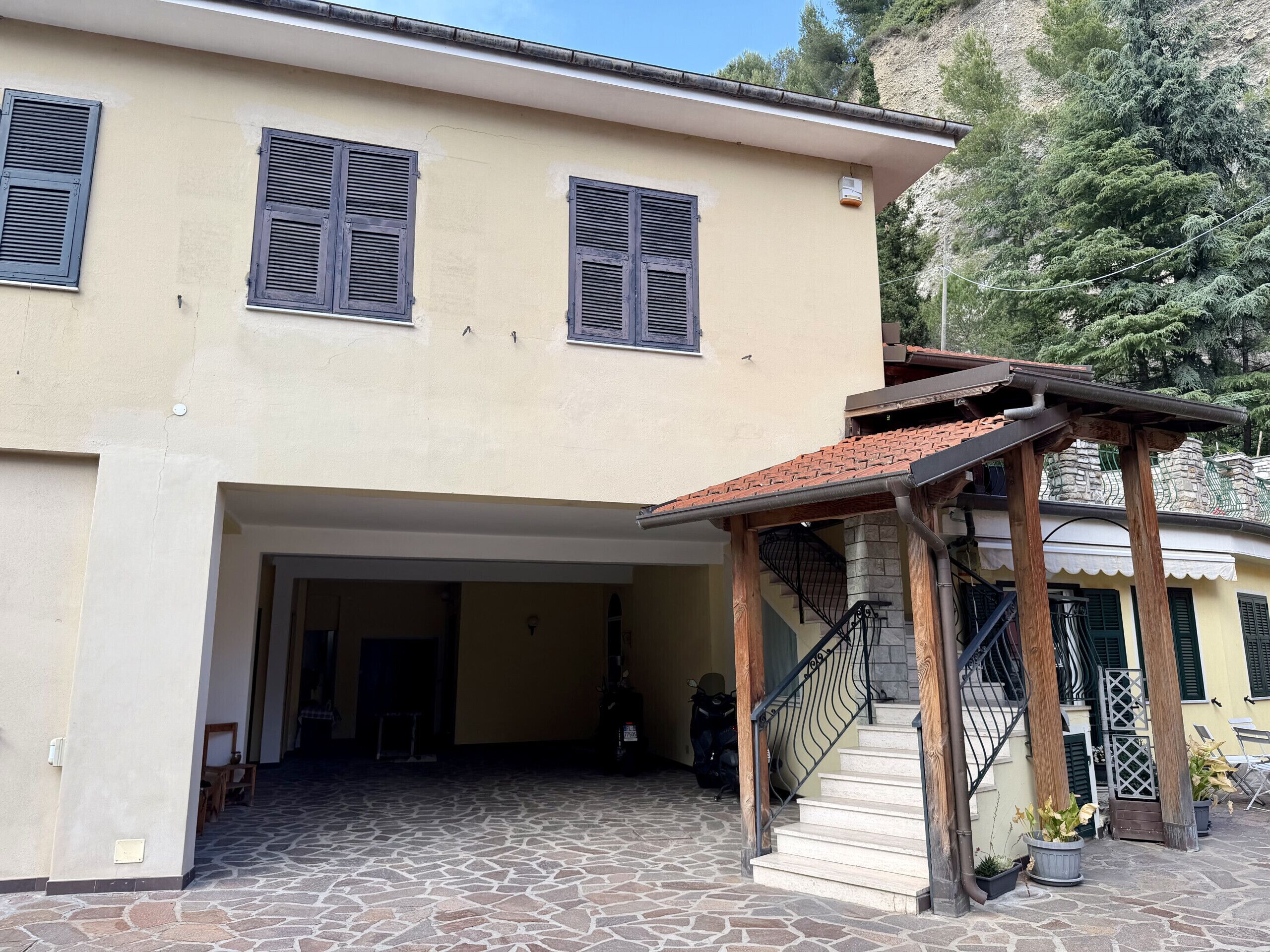 Ein Gebäude mit steinbelagtem Eingangsbereich, einer Veranda und einer Treppe mit Metallgeländer.