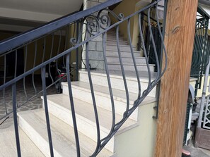 Eine Treppe mit Metallgeländer, einem Holzpfosten und einem geparkten Fahrzeug im Hintergrund.