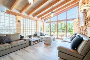 A spacious living area with wooden beams, large windows, and a fireplace.