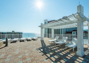 Eine Dachterrasse mit Liegestühlen, einer Pergola und Meerblick.