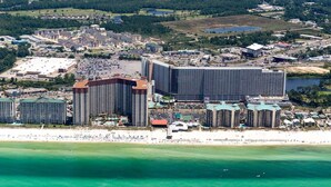 Ett hotellkomplex vid kusten med flera höga byggnader, en strand och en småbåtshamn.