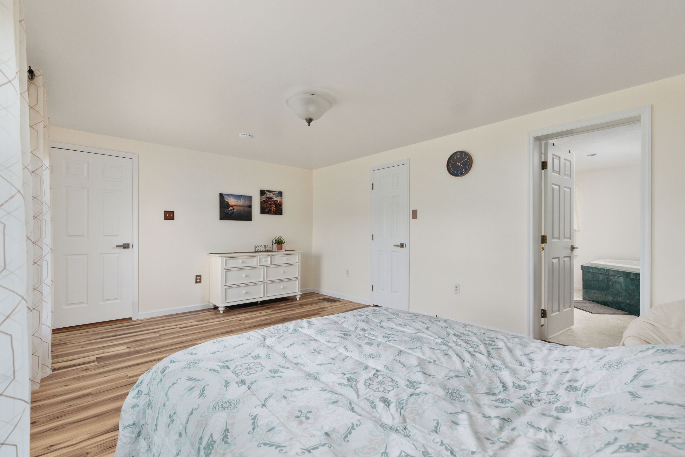 Un dormitorio con cama, cómoda y dos puertas.